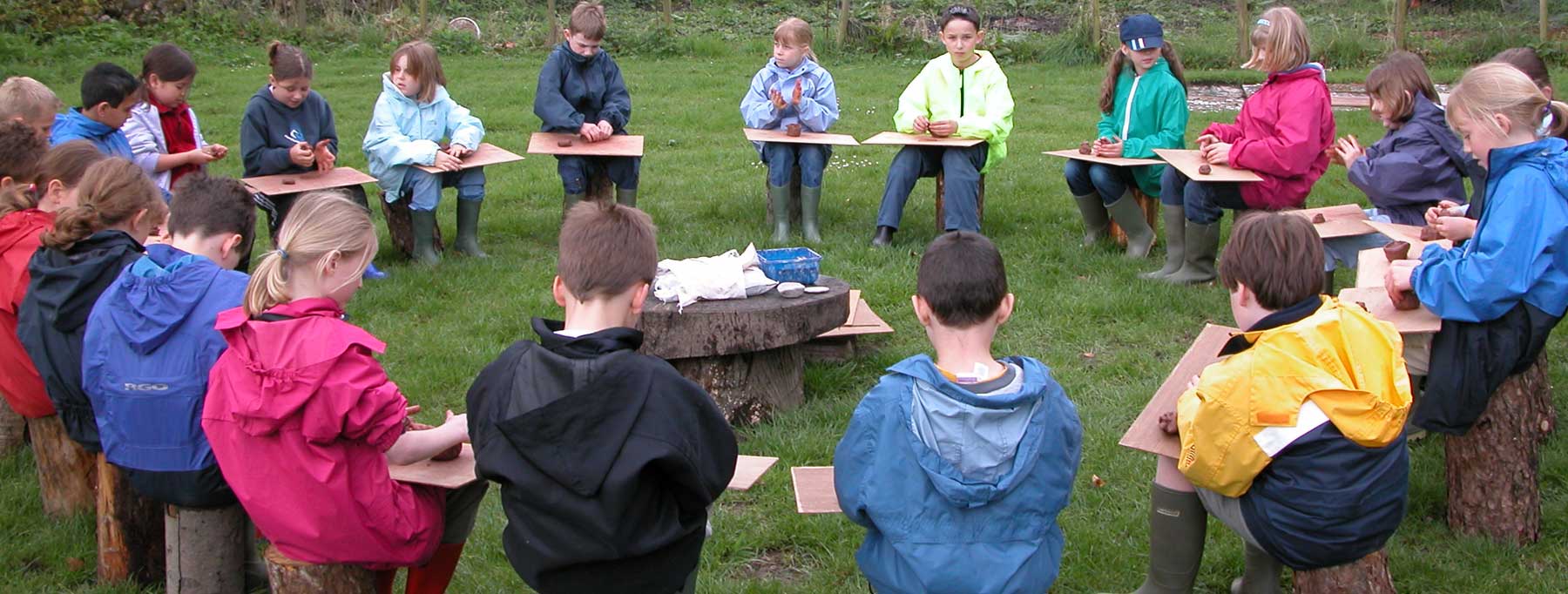 Children sat in a circle learning how to work clay as done in the Stone Age