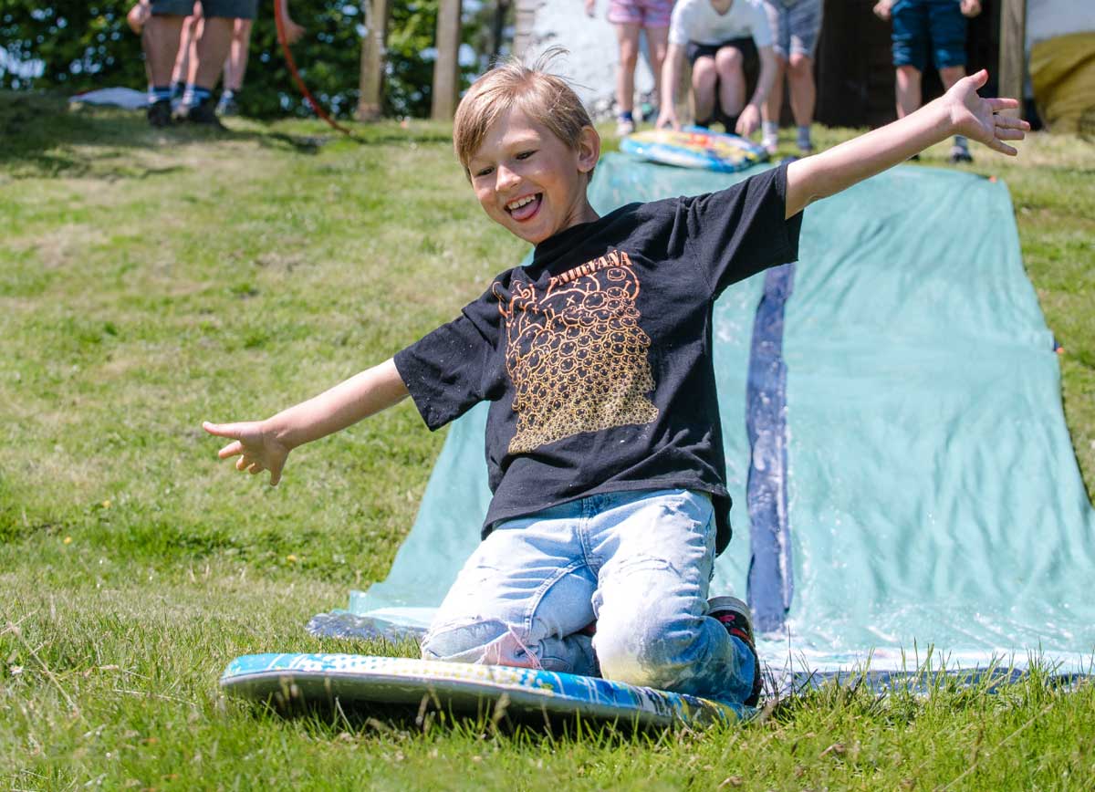 Boy learning about forces by sliding down a hill on a water slide